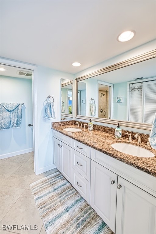 full bath featuring double vanity, baseboards, a shower, and a sink