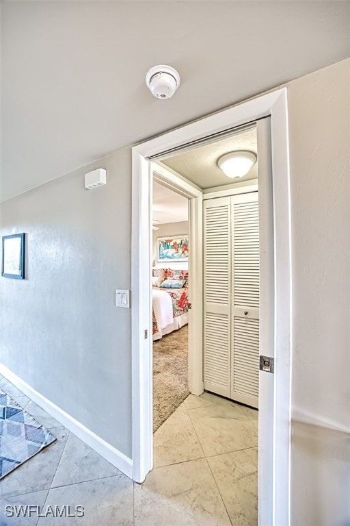 hall featuring light tile patterned flooring, light colored carpet, and baseboards