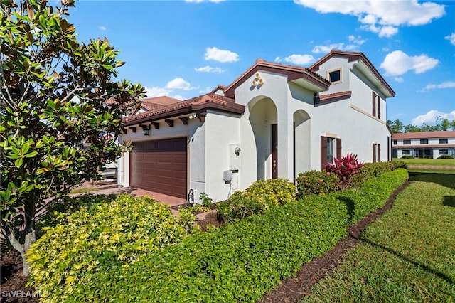 exterior space featuring a garage, a tile roof, a front yard, and stucco siding