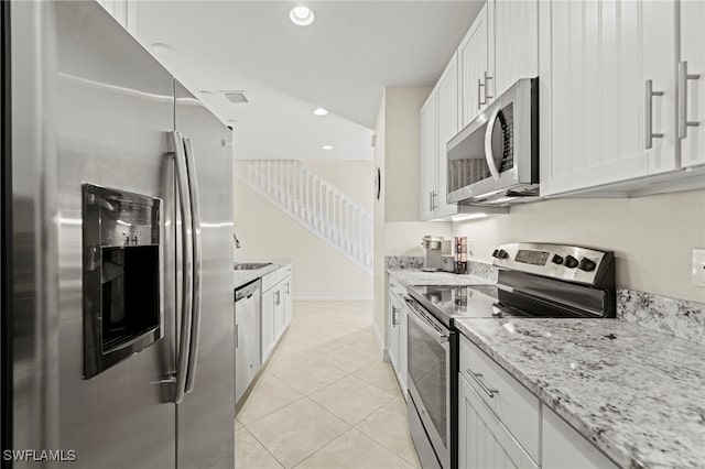 kitchen with light tile patterned floors, stainless steel appliances, recessed lighting, white cabinets, and light stone countertops