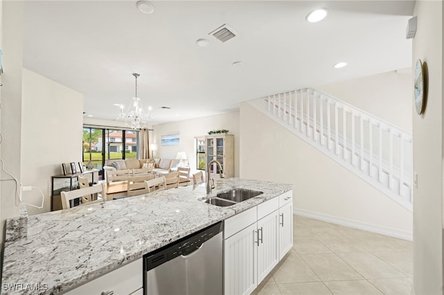 kitchen with light stone counters, visible vents, stainless steel dishwasher, white cabinets, and a sink