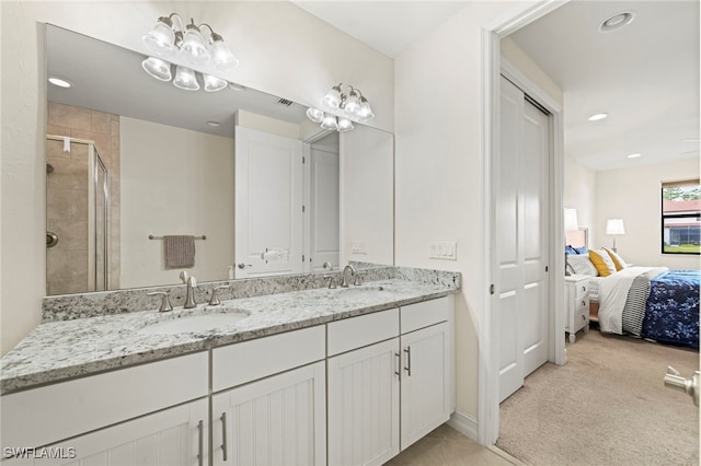 ensuite bathroom with double vanity, a stall shower, a sink, and recessed lighting