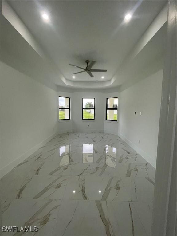 spare room with baseboards, ceiling fan, marble finish floor, a tray ceiling, and recessed lighting