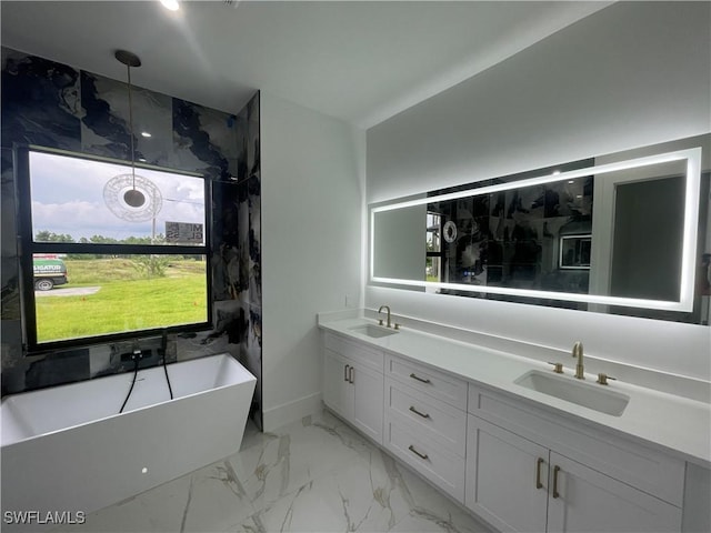 full bath featuring marble finish floor, double vanity, a soaking tub, and a sink