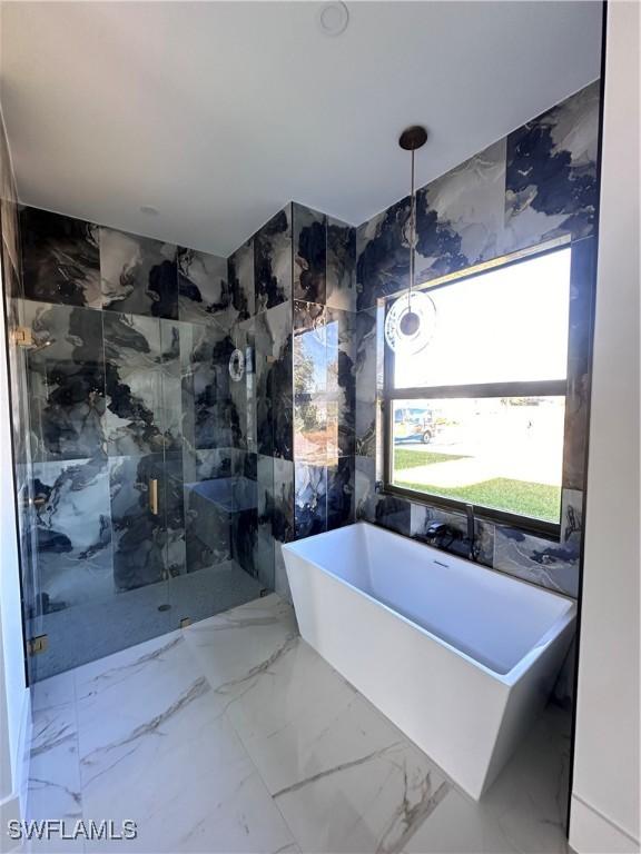 bathroom featuring marble finish floor, a soaking tub, and a marble finish shower