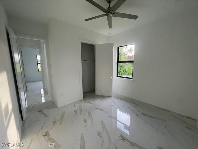 unfurnished bedroom featuring ceiling fan, marble finish floor, a closet, and baseboards