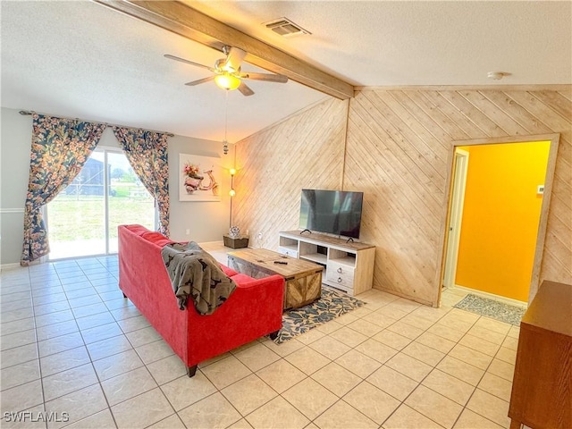 living area featuring wooden walls, visible vents, vaulted ceiling with beams, and a textured ceiling