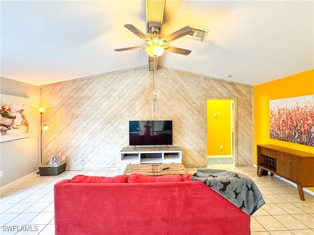 tiled living area featuring ceiling fan, an accent wall, baseboards, and beamed ceiling