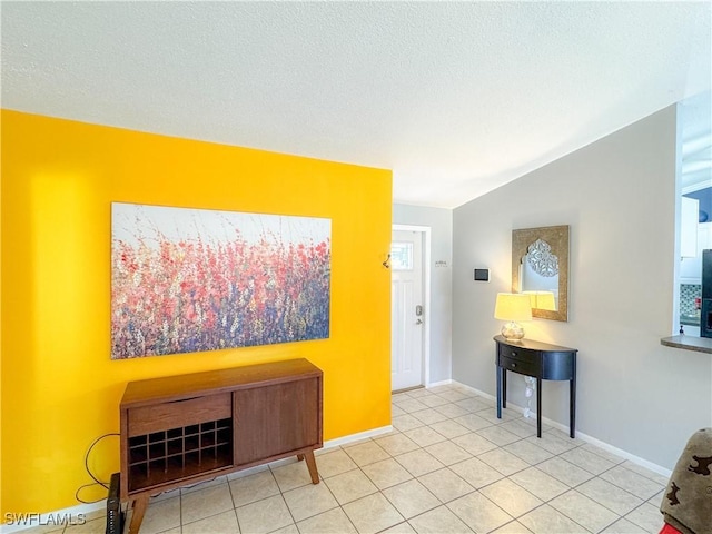 interior space with baseboards, vaulted ceiling, and a textured ceiling