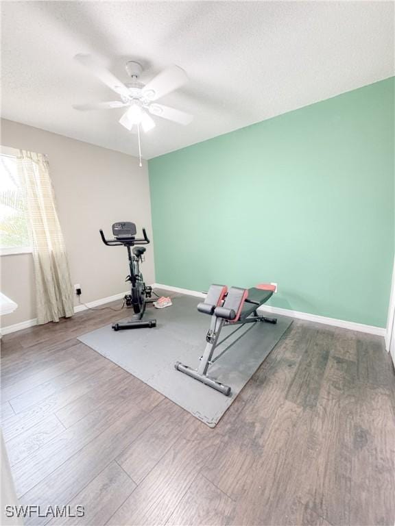 workout area featuring ceiling fan, a textured ceiling, baseboards, and wood finished floors