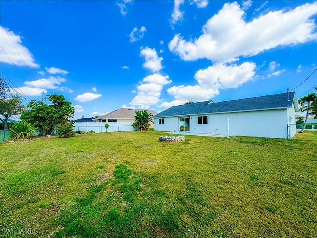 back of house featuring a yard, a fenced backyard, and stucco siding