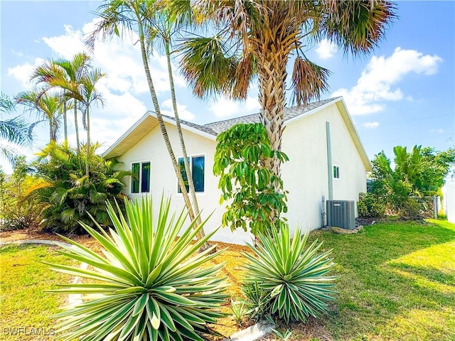 view of home's exterior with central air condition unit, a yard, and stucco siding