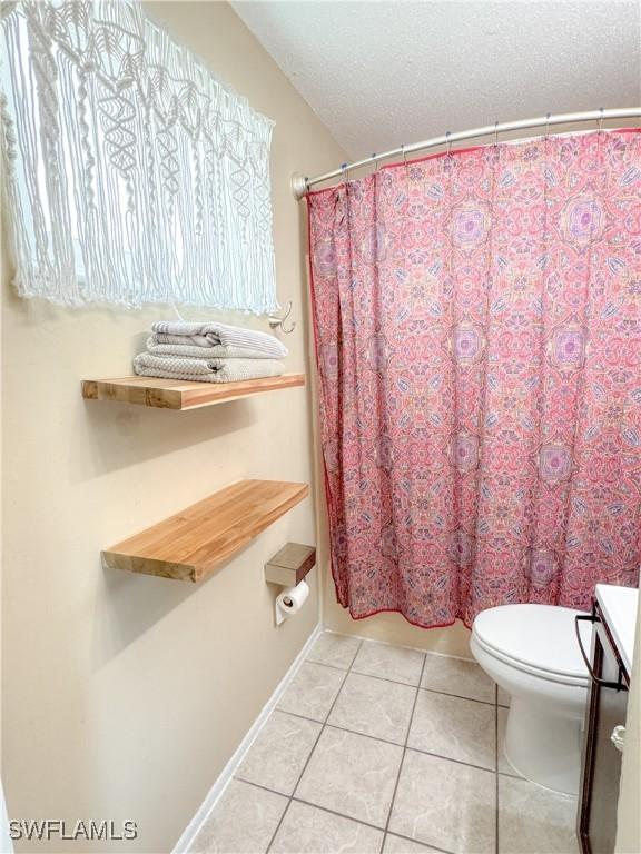 bathroom featuring a shower with shower curtain, a textured ceiling, toilet, and tile patterned floors