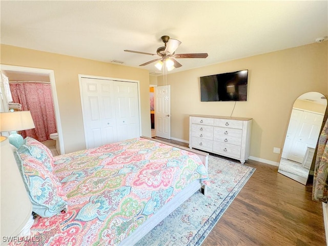 bedroom featuring arched walkways, a closet, visible vents, wood finished floors, and baseboards