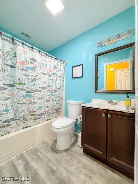 bathroom with toilet, wood finished floors, vanity, visible vents, and shower / bathtub combination with curtain