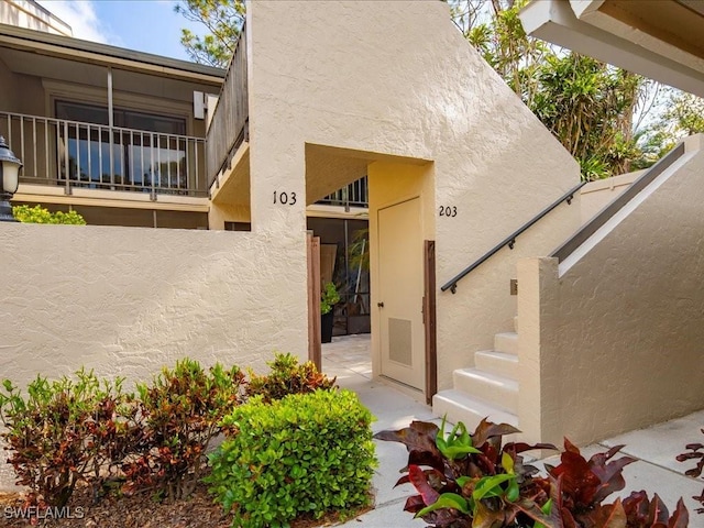 doorway to property with fence and stucco siding