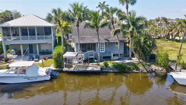 back of house featuring a water view, a sunroom, stairs, and a patio