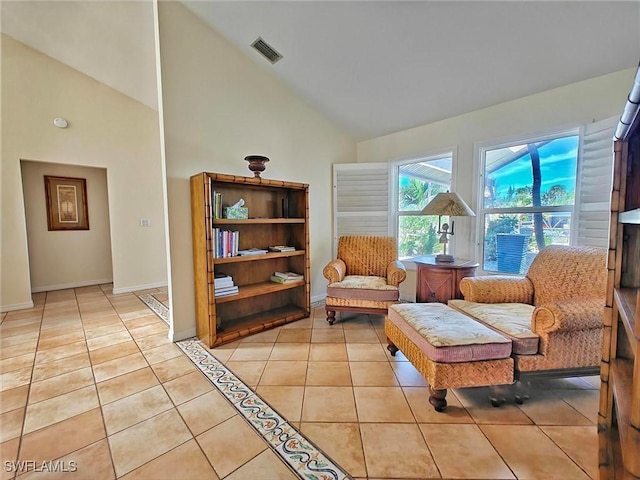 living area with high vaulted ceiling, light tile patterned flooring, visible vents, and baseboards