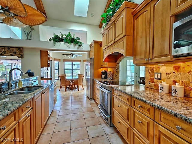 kitchen with stainless steel appliances, light tile patterned flooring, a sink, and brown cabinets