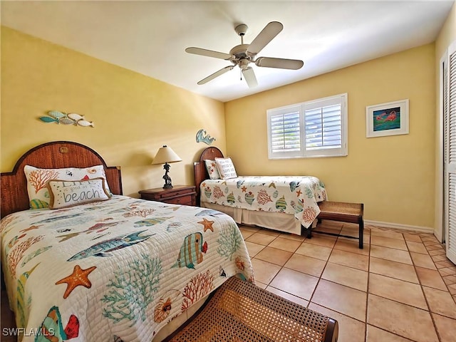 bedroom with a ceiling fan, tile patterned flooring, a closet, and baseboards