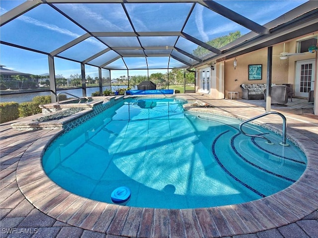 view of pool featuring a patio, a pool with connected hot tub, a water view, a ceiling fan, and glass enclosure