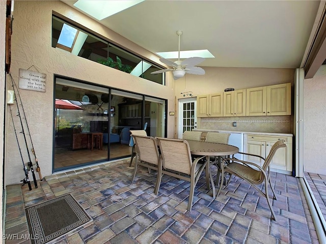 dining area with a ceiling fan, a skylight, a textured wall, and high vaulted ceiling