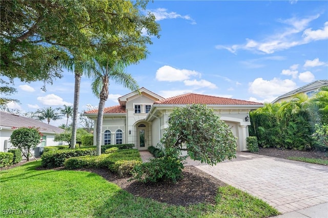 mediterranean / spanish house featuring decorative driveway, a tile roof, stucco siding, a front yard, and a garage