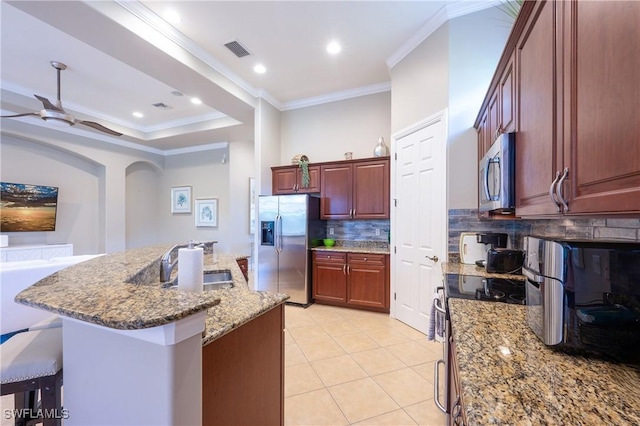 kitchen featuring a breakfast bar area, stainless steel appliances, a sink, visible vents, and crown molding