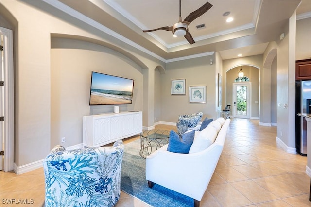 living area with arched walkways, a raised ceiling, visible vents, a ceiling fan, and light tile patterned flooring