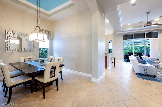 dining room with light tile patterned flooring, plenty of natural light, a tray ceiling, and ornamental molding