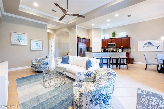 living room with visible vents, arched walkways, a tray ceiling, and light tile patterned flooring