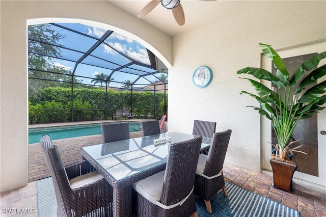 view of patio featuring a lanai, an outdoor pool, and a ceiling fan