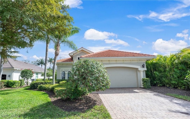 mediterranean / spanish-style home with a garage, a tiled roof, decorative driveway, stucco siding, and a front lawn