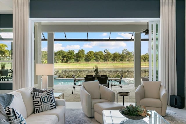 sunroom with a ceiling fan and a water view