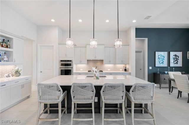 kitchen with visible vents, white cabinets, a kitchen breakfast bar, light countertops, and stainless steel double oven