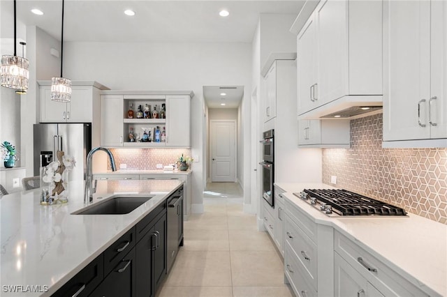 kitchen with white cabinets, stainless steel appliances, under cabinet range hood, a sink, and light tile patterned flooring