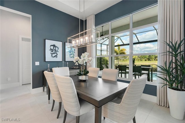 dining space with a towering ceiling, light tile patterned floors, baseboards, and a notable chandelier