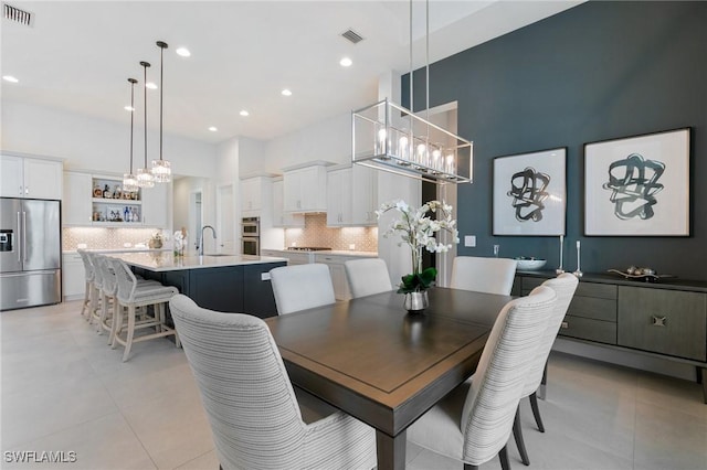 dining area featuring an inviting chandelier, a high ceiling, visible vents, and light tile patterned floors