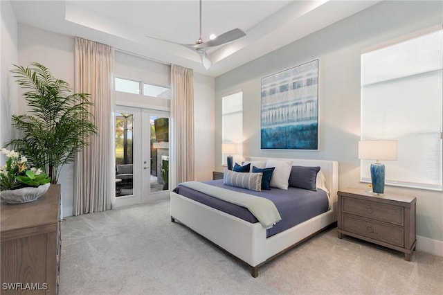 bedroom featuring access to exterior, a tray ceiling, french doors, carpet, and ceiling fan