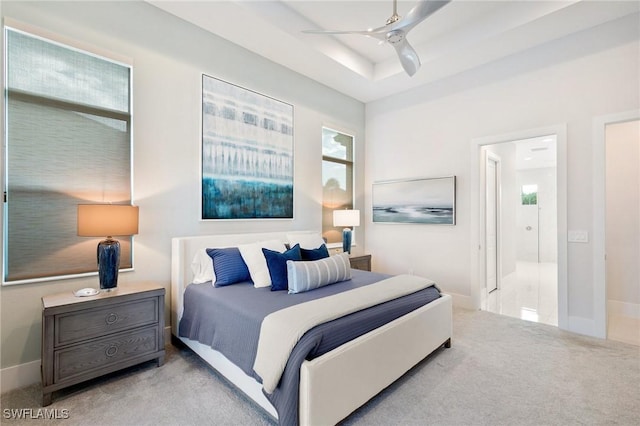 bedroom featuring carpet, a tray ceiling, ceiling fan, and baseboards