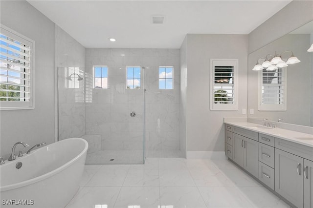 bathroom featuring a walk in shower, marble finish floor, a freestanding tub, and a sink