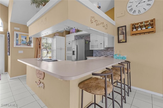 kitchen with stainless steel fridge with ice dispenser, white microwave, a peninsula, a sink, and backsplash