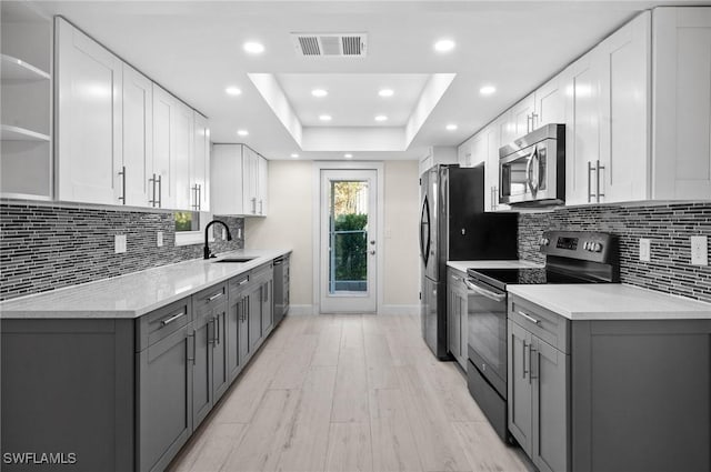 kitchen featuring range with electric cooktop, visible vents, stainless steel microwave, gray cabinetry, and a sink