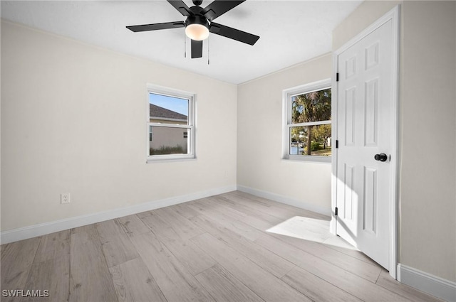 empty room with wood finished floors, a ceiling fan, and baseboards