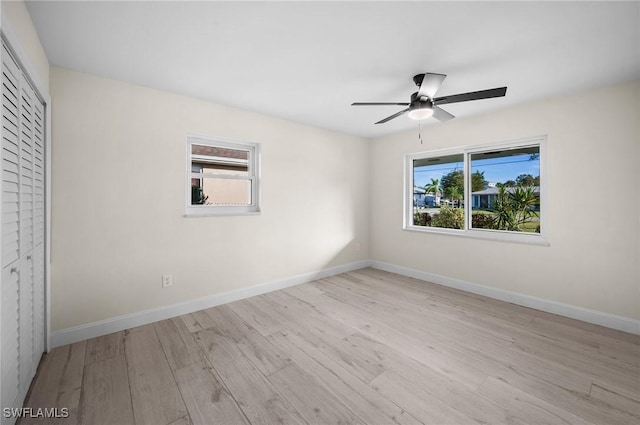 unfurnished bedroom featuring multiple windows, baseboards, and wood finished floors