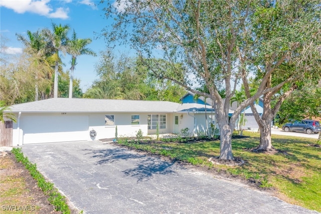 ranch-style house with a garage, stucco siding, and aphalt driveway