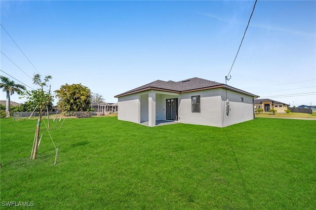 back of property with stucco siding, a lawn, and fence