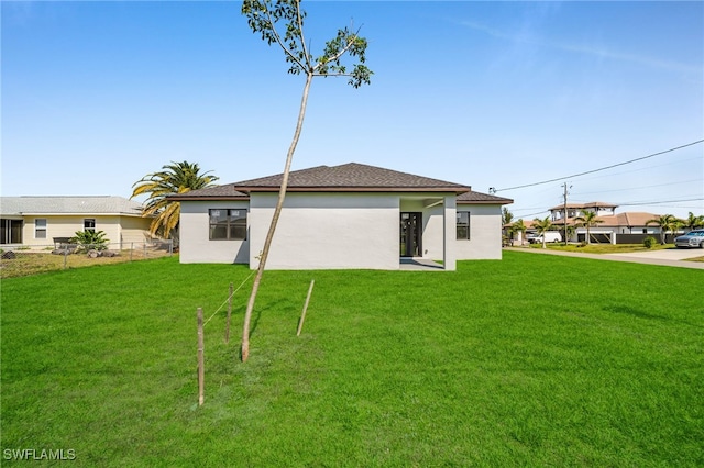 rear view of house with a lawn and stucco siding