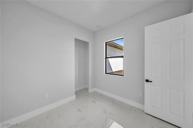 empty room featuring visible vents, marble finish floor, and baseboards