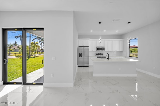 kitchen with visible vents, an island with sink, a sink, stainless steel appliances, and white cabinets